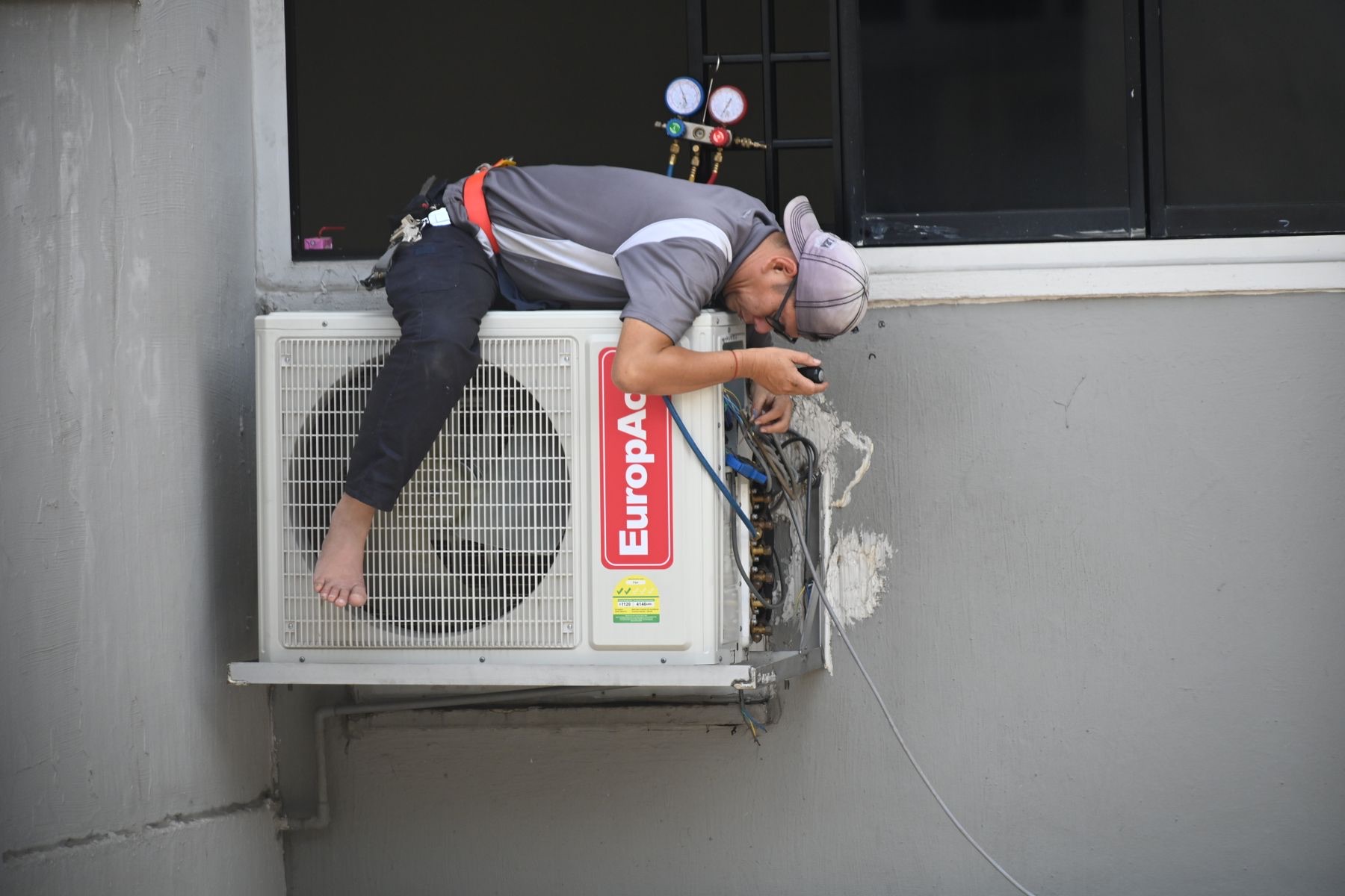 Technician repairing a wall-mounted air-conditioning unit on an urgent service call