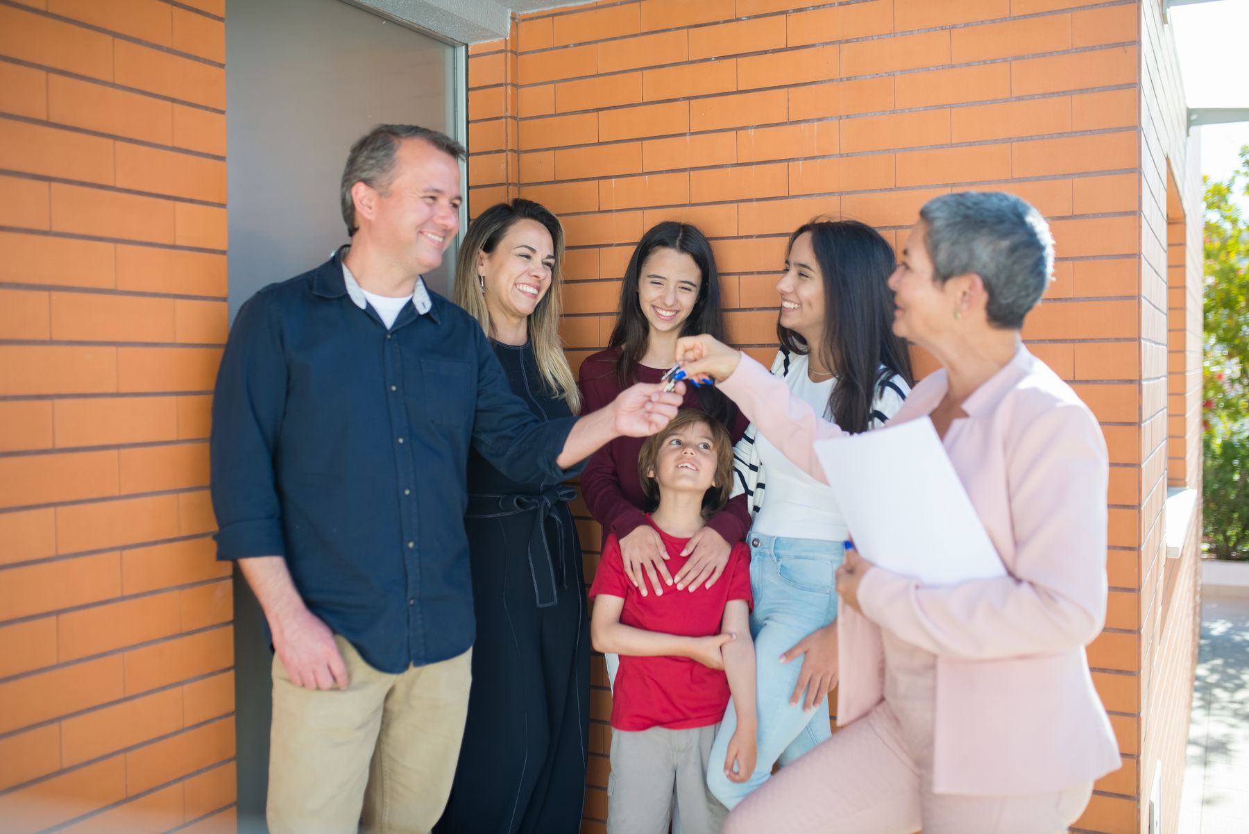 Real estate agent handing keys to a smiling family at a front door